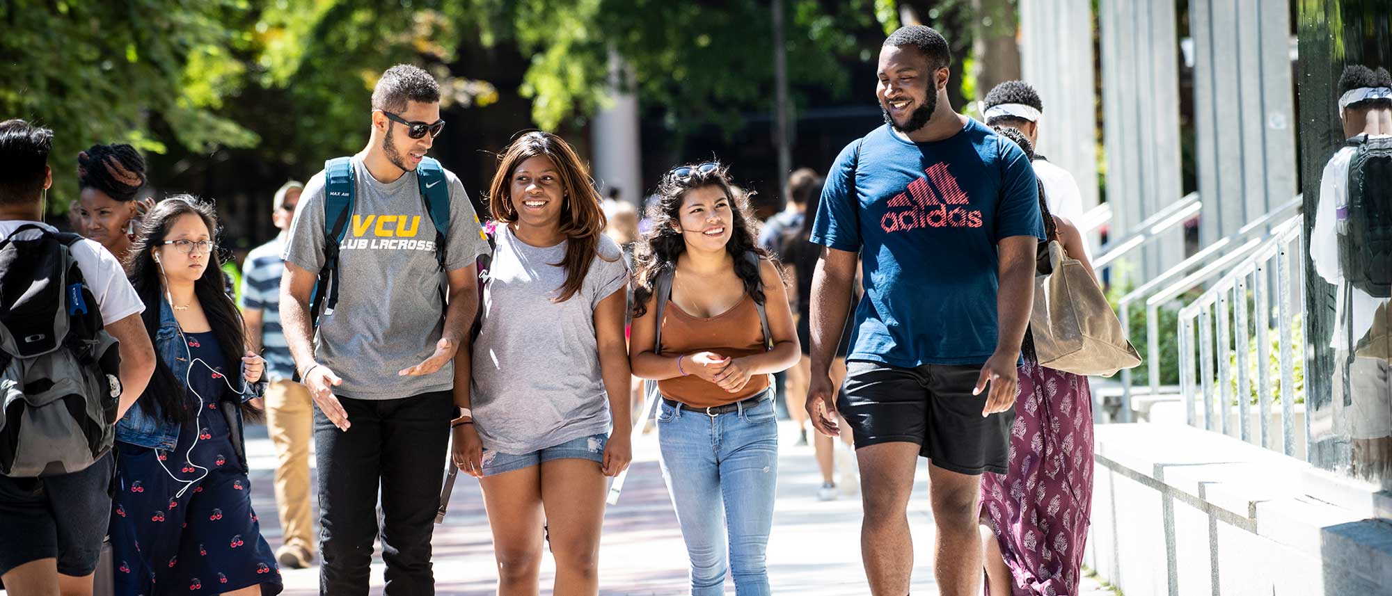 four v.c.u. students walking across campus on a sunny day